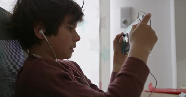 Egy Fiatal Fiú Fejhallgatóval Játszik Egy Kézi Videojátékot Kifejezése Koncentráció — Stock videók