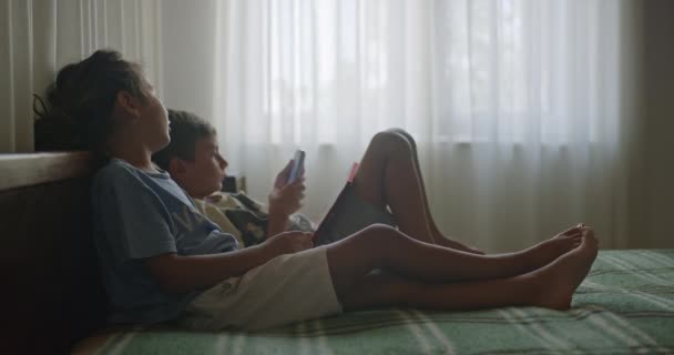 소년이 디지털 태블릿에 침대에서 아이가 평온하고 햇볕이 침실에서 누워있습니다 — 비디오