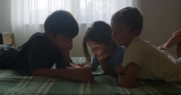 Três Crianças Deitam Uma Cama Interagindo Intimamente Uma Sala Com — Vídeo de Stock