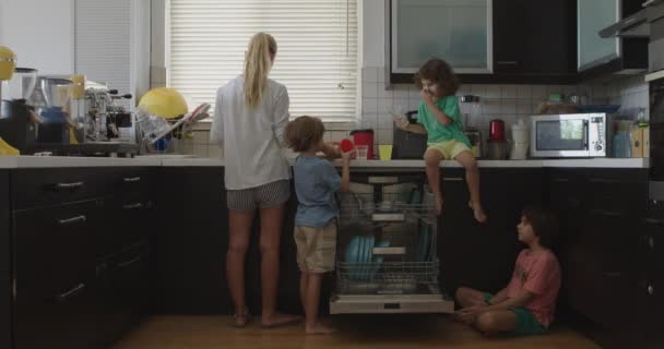 Мать Контролирует Своих Детей Поскольку Помогают Загружать Посуду Посудомоечную Машину — стоковое видео