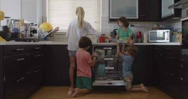 어머니는 아이들이 세척기에 요리를 적재하는 협력과 가족의 책임감을 키우는 감독합니다 — 비디오