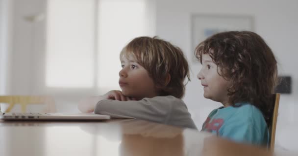 两个小男孩坐在客厅的桌子旁 全神贯注地坐在笔记本电脑的屏幕上 — 图库视频影像