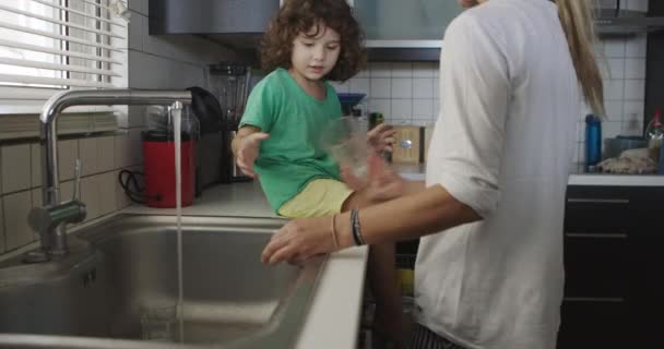 Ein Kleiner Junge Der Auf Einer Arbeitsplatte Sitzt Hilft Seiner — Stockvideo