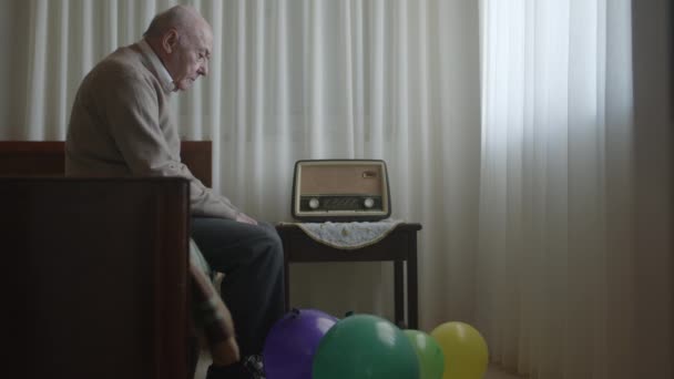 Ένας Ηλικιωμένος Κύριος Κάθεται Μια Καρέκλα Δίπλα Ένα Ραδιόφωνο Περικυκλωμένος — Αρχείο Βίντεο