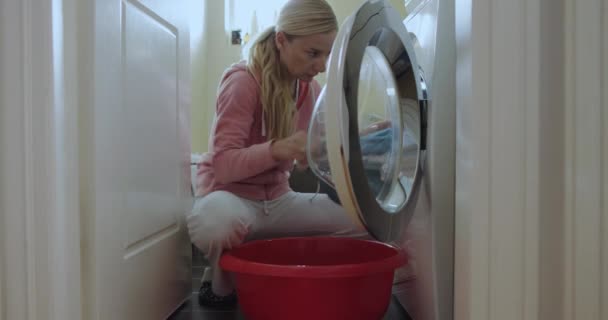 Young Woman Crouches Front Loading Washing Machine Seemingly Preparing Laundry — Stock Video