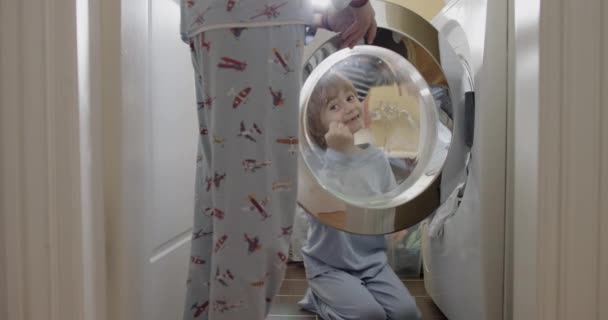Ein Kleines Kind Sitzt Zufrieden Einer Waschküche Und Blickt Neben — Stockvideo