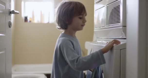 Menino Com Cabelo Loiro Está Frente Uma Máquina Lavar Roupa — Vídeo de Stock