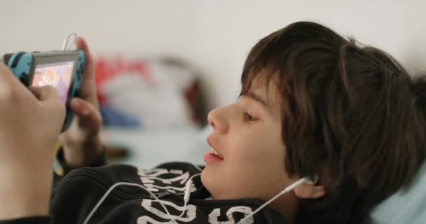 Niño Yace Cómodamente Cama Enfocado Intensamente Consola Juegos Mano Que — Vídeos de Stock