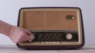 Bir kadının eski moda bir radyonun düğmelerini basit bir arka plana ayarlayıp, nostalji hissi uyandıran yakın plan görüntüsü..