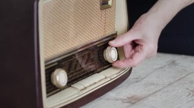 Bir kadının eski moda bir radyonun düğmelerini basit bir arka plana ayarlayıp, nostalji hissi uyandıran yakın plan görüntüsü..