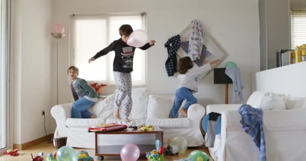 Tre Bambini Stanno Saltando Energicamente Divano Bianco Circondato Giocattoli Oggetti — Video Stock