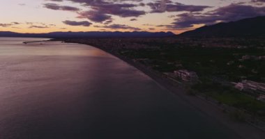 Alacakaranlıkta Kalamata Kasabası 'nın hava manzarası, kasabanın çevresindeki deniz üzerinde parlayan ufku gösteriyor. Günbatımının renkleri nazikçe gökyüzünü aydınlatır..