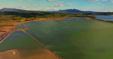Voidokilia Sahili 'nin sakin kıvrımları yukarıdan çekiliyor, turkuaz berrak suların altın kumlu plaja hafifçe dokunduğunu gösteriyor..