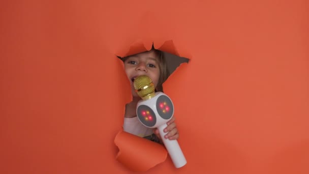 Playful Boy Pops His Face Torn Orange Paper Backdrop Bright — Vídeo de Stock