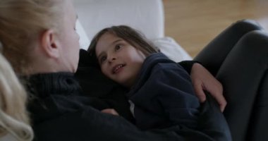 Oğluna sarılan bir anne, oturma odasının sıcak atmosferinde rahatça dinlenirken bir anlık sevgi paylaşıyor..