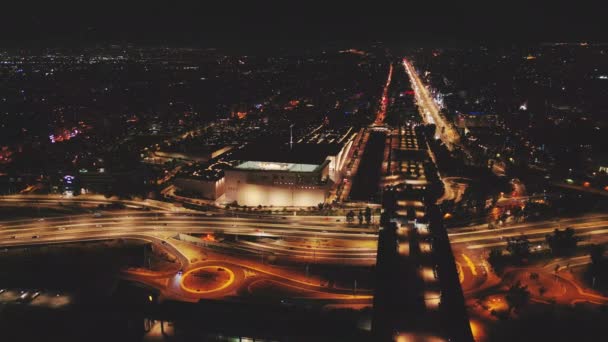 忙しい街の交差点を眺める夜間ドローンアイビューは 曲線ハイウェイに沿って動いている車の輝くライトを示しています — ストック動画