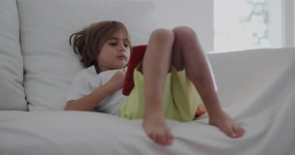 Beyaz Bir Kanepeye Uzanmış Bir Çocuk Dijital Tabletine Dalmış Öğle — Stok video