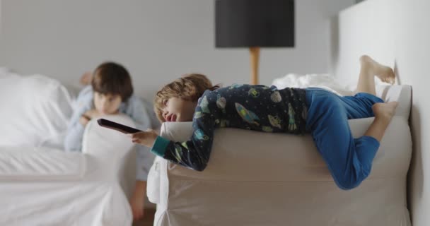 Två Barn Lounge Försiktigt Ett Vardagsrum Ligger Soffa Med Avlägsen — Stockvideo