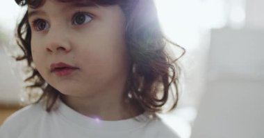 Küçük bir çocuk, uzay temalı bir pijama setiyle evin içinde duruyor, aydınlık bir odada duruyor, rahatlamış, ağlayan.