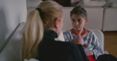 Bir anne, genç oğlunu azarlarken görülüyor. Oğlu özenli ve muhtemelen pişman görünüyor. Evlerinin tanıdık ortamında..