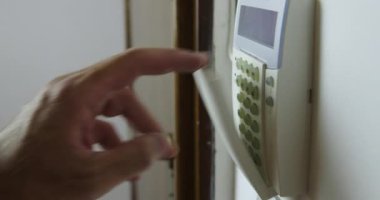 Bir adamın eli, güvenlik ve güvenliği sağlamak için duvarlara monte edilmiş bir tuş takımına alarm yerleştirirken yakalanır..