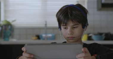 Elinde tuttuğu dijital tablet üzerinde yoğunlaşan diş teli olan genç bir çocuğun yakın çekim görüntüsü, muhtemelen eğitici bir aktiviteye veya dijital bir eğlenceye bağlanıyor..