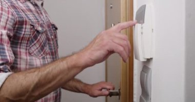 Erkek eli evin güvenlik alarm sistemine bir kod girerken yakın plan görüntüsü evin güvenliğini sağlar..