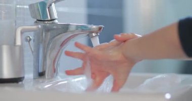 Genç bir çocuk banyo lavabosunda sabun ve suyla ellerini titizlikle yıkarken görülüyor. Sabunlu sabunlu sabunlu sabunlu sabunlu sabunlu sabunlu sabunlu sabunlu sabunlu temizliği rutininin bir parçası olarak..