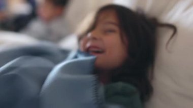 Genç bir çocuk neşeyle gülümsüyor, battaniyeye sarılıp, gün boyunca kanepede dinleniyor..