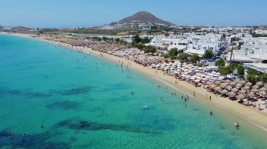 İnsanlar Naxos 'taki Agios Prokopios Sahili' nin kumlu sahillerinde şemsiyelerin altında yüzmeyi ve dinlenmeyi seviyorlar..