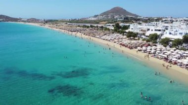 İnsanlar Naxos 'taki Agios Prokopios Sahili' nin kumlu sahillerinde şemsiyelerin altında yüzmeyi ve dinlenmeyi seviyorlar..