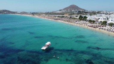 İnsanlar Naxos 'taki Agios Prokopios Sahili' nin kumlu sahillerinde şemsiyelerin altında yüzmeyi ve dinlenmeyi seviyorlar..