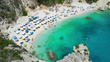Yunanistan 'ın Lefkada kentinde turkuaz su ve güneş banyosu yapan güzel bir plaj manzarası..
