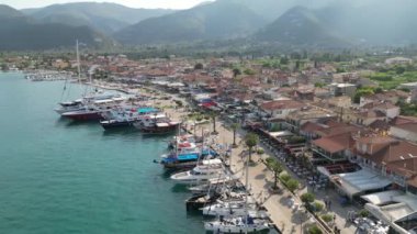 Yunanistan 'ın Lefkada kentindeki limanın hava manzarasında restoran, kafe ve dükkanlarla çevrili canlı bir rıhtım manzarası görülüyor. Sakin sular tekneler ve yatlarla dolu..