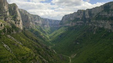 A breathtaking view of Vikos Gorge in Greece, with its steep rock faces and verdant slopes stretching into the distance. clipart
