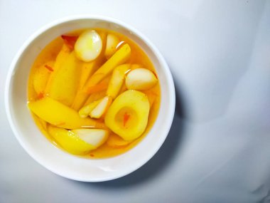 Ev yapımı Asinan, su ve şekerle karıştırılmış taze mango turşusu ve dilimlenmiş yılan meyvesidir. Beyaz arkaplanda izole.