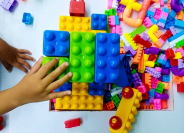 Bir çocuğun en iyi görüntüsü renkli yapı taşları ve beyaz arka plandaki oyuncak tuğlalarla oynamaktır.