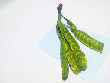 Beyaz arka planda parkia speciosa (petai, acı fasulye, bükülmüş fasulye, kokuşmuş fasulye).