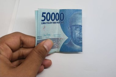 El ele tutuşan 50 rupiah banknot beyaz bir arkaplanda izole edilmiş.