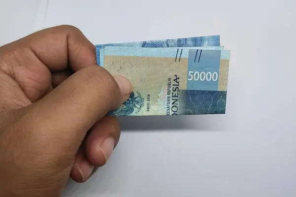 El ele tutuşan 50 rupiah banknot beyaz bir arkaplanda izole edilmiş.