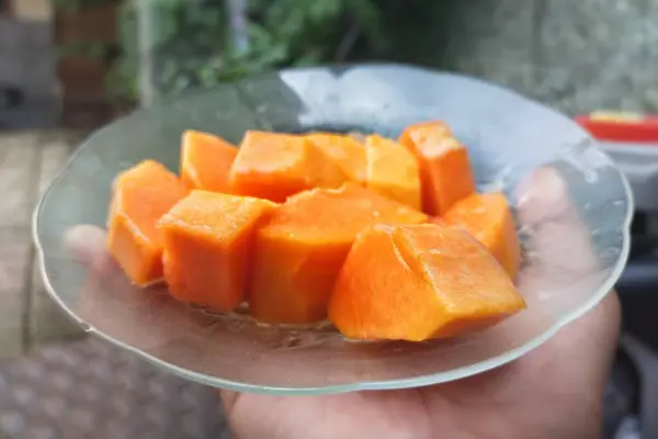 Tahta arka planda bir kasede taze ve sağlıklı papaya meyvesi.