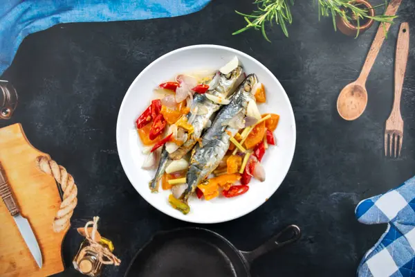 Sebzeli kızarmış balık ve mavi arka planda baharat. en üstteki görünüm.