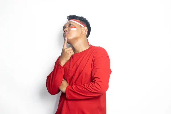 Asyalı bir adamın portresi, kırmızı tişört ve çenesinde işaret parmağı olan kırmızı ve beyaz saç bandı. Endonezya bağımsızlık günü, beyaz arka planda izole