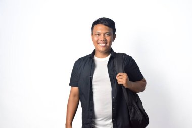 Sıradan kıyafetler giyen Asyalı genç adam gülümsüyor ve bir sırt çantası taşıyor. 