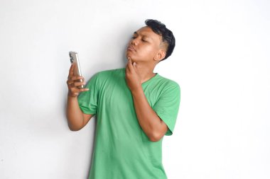 Cep telefonlu Asyalı bir adamın çenesine dokunduğunu düşünüyor. 