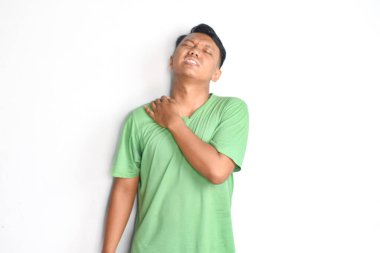 Yeşil giyen genç adam beyaz arka planda boyun ağrısından muzdarip..