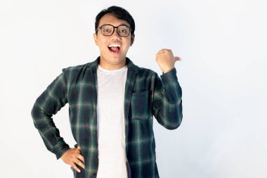 Asyalı gülümseyen genç bir adamın portresi, izole edilmiş beyaz bir arka planda başparmağıyla yan tarafı gösteriyor. Reklamlar, promosyonlar ve sunum modelleri için mükemmel..