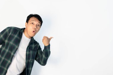 Yakışıklı Asyalı genç adam başparmağını yana kaldırdı, şaşırdı ve şaşırdı, şaşırdı, şaşırdı, korku ve heyecan dolu beyaz arka plan
