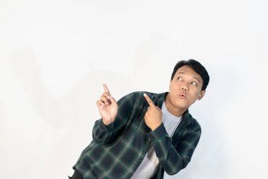 Yeşil tişörtlü Asyalı adamın şok olmuş yüzü sol elinde boş bir yeri işaret ediyor..