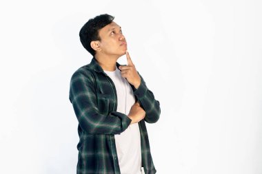 Asyalı bir adam tecrit edilmiş arka planda duruyor, parmak çenesinde şüpheyi düşünüp kafasını kaldırıyor.